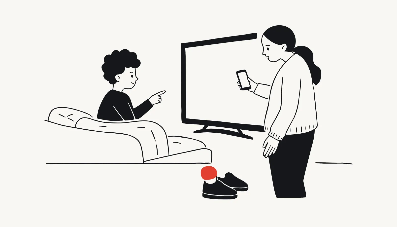 At home, the boy points at the TV while the parent checks her own phone.